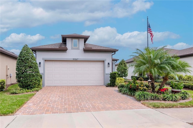 view of front of property featuring an attached garage, decorative driveway, and stucco siding