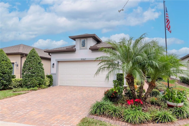 view of front of house featuring a garage, decorative driveway, and stucco siding