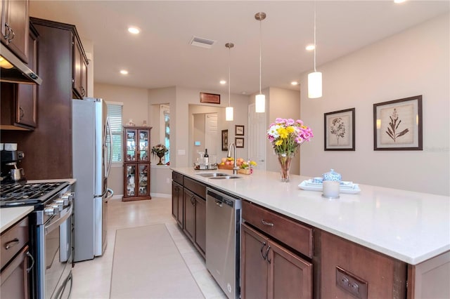 kitchen featuring decorative light fixtures, a large island, stainless steel appliances, light countertops, and a sink