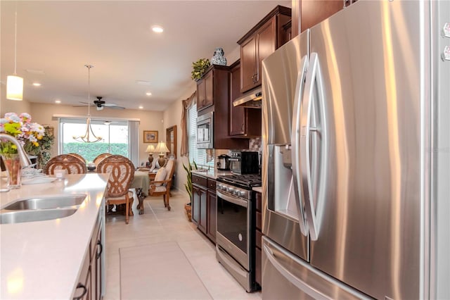 kitchen with dark brown cabinetry, under cabinet range hood, stainless steel appliances, a sink, and light countertops