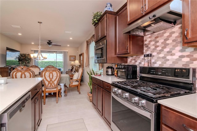 kitchen featuring stainless steel appliances, light countertops, hanging light fixtures, and under cabinet range hood