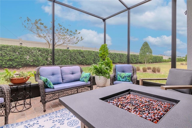 view of patio with a lanai, fence, and an outdoor living space with a fire pit