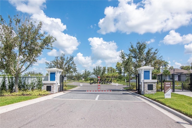 view of street with curbs, a gated entry, and a gate