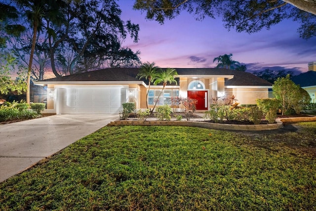 ranch-style home with a garage and a yard