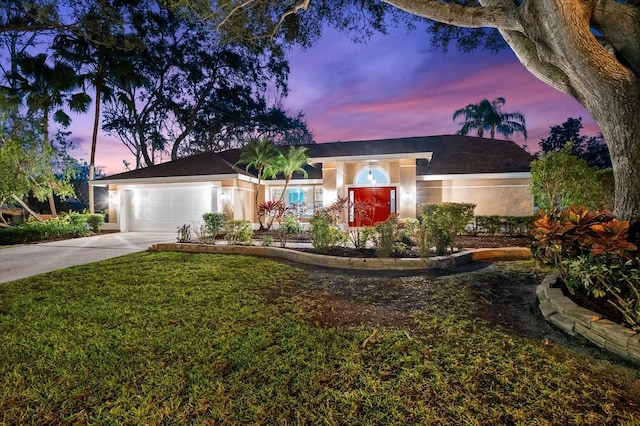 ranch-style home featuring a garage, driveway, a front yard, and stucco siding