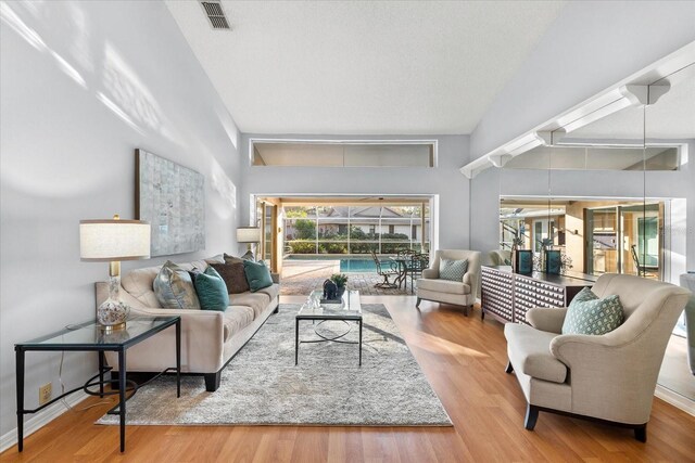 living room with high vaulted ceiling, visible vents, and wood finished floors