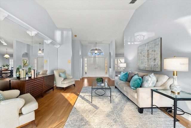 living area featuring high vaulted ceiling, visible vents, and wood finished floors