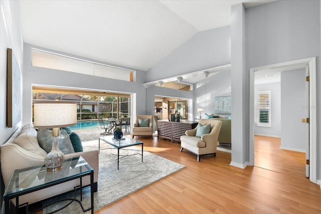 living room with high vaulted ceiling, wood finished floors, and baseboards