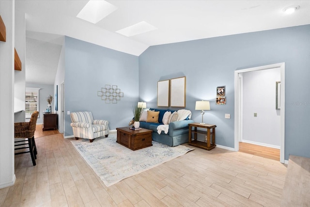 living room with light wood-type flooring, vaulted ceiling with skylight, and baseboards