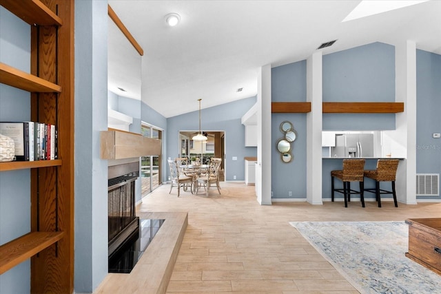 living room featuring lofted ceiling, visible vents, a tiled fireplace, and wood finished floors