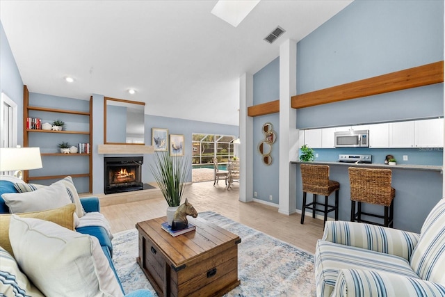 living area with a skylight, visible vents, light wood-style floors, a lit fireplace, and baseboards