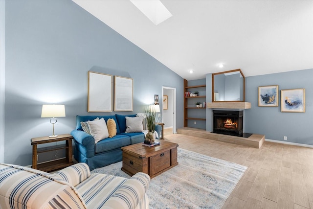 living room with recessed lighting, a large fireplace, wood finished floors, vaulted ceiling with skylight, and baseboards