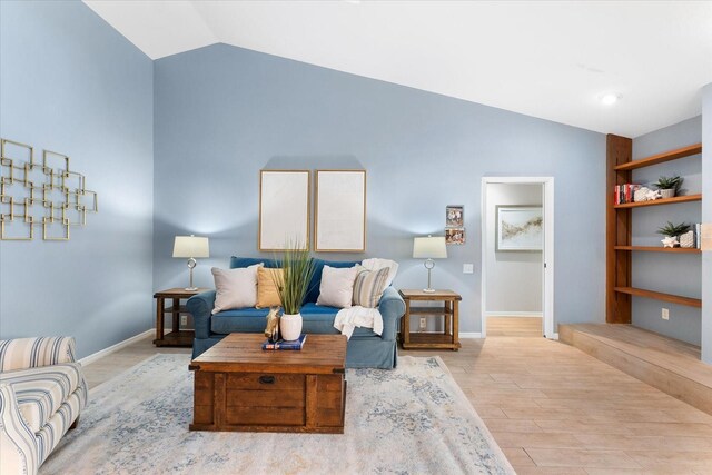 living area featuring baseboards, vaulted ceiling, and wood finished floors