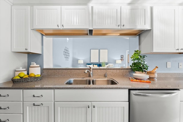 kitchen with a sink, white cabinetry, light stone counters, and stainless steel dishwasher