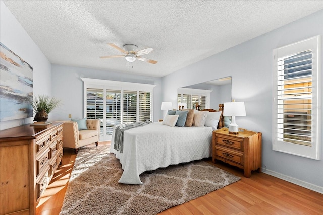 bedroom with ceiling fan, a textured ceiling, wood finished floors, and baseboards