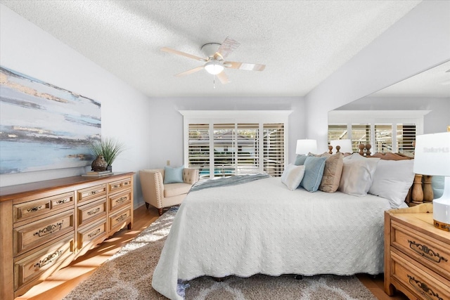 bedroom featuring a textured ceiling, ceiling fan, and light wood-style floors