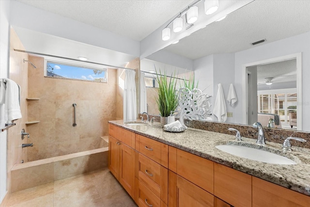 bathroom featuring visible vents, a sink, and a tile shower