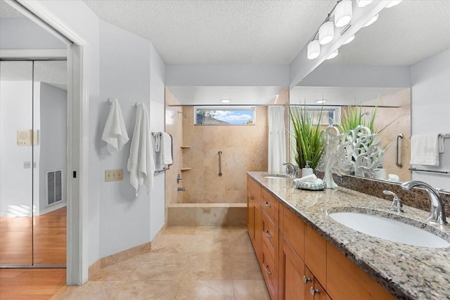 full bath featuring tiled shower / bath combo, visible vents, a sink, and a textured ceiling