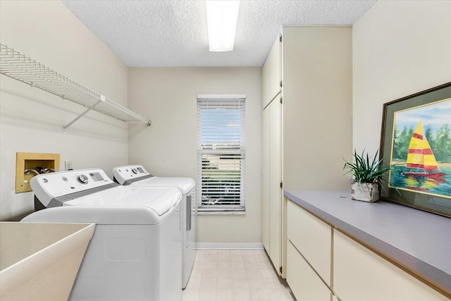 clothes washing area with laundry area, baseboards, a textured ceiling, separate washer and dryer, and a sink