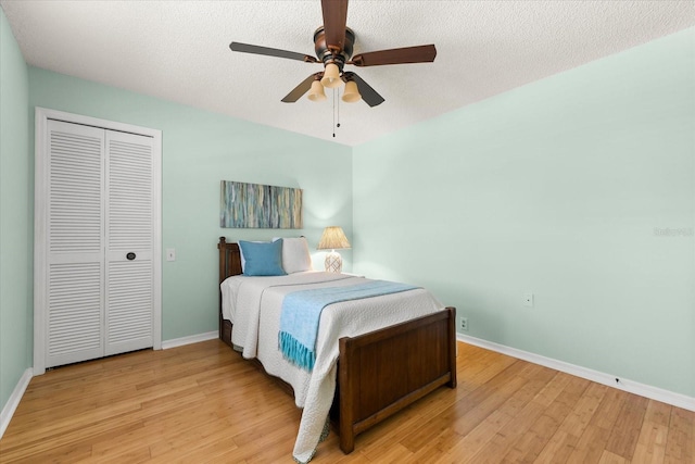 bedroom with a closet, light wood-style flooring, baseboards, and a textured ceiling