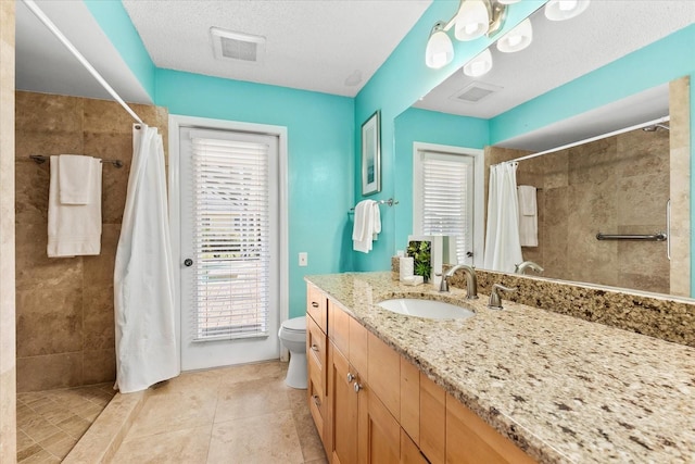 bathroom featuring tiled shower, vanity, toilet, and tile patterned floors