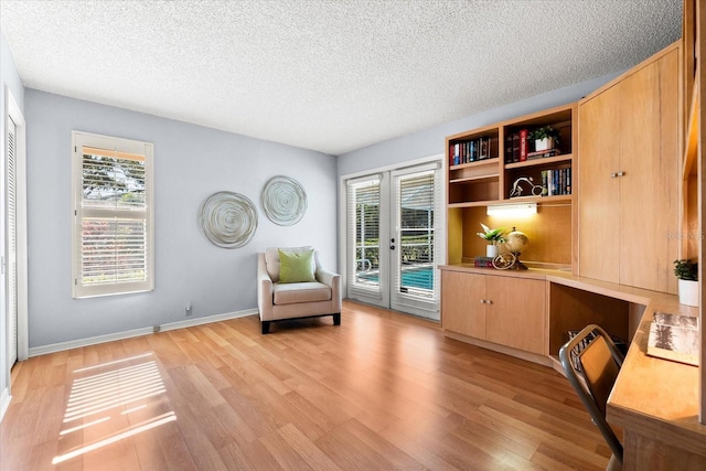 living area featuring light wood-type flooring, a healthy amount of sunlight, and built in study area