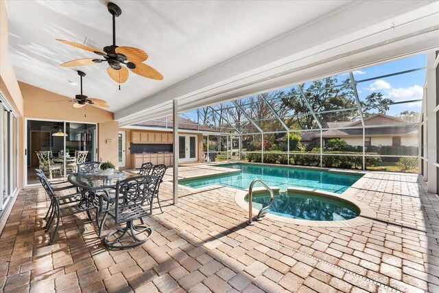 view of pool with a patio, a lanai, a pool with connected hot tub, a ceiling fan, and french doors