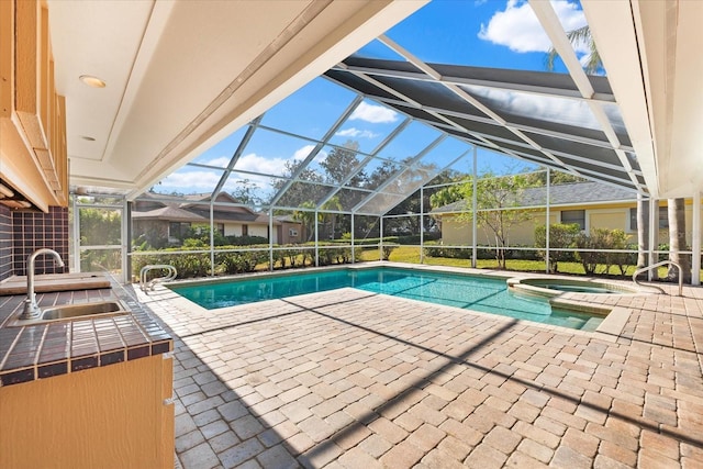 view of swimming pool featuring a lanai, a pool with connected hot tub, a sink, and a patio