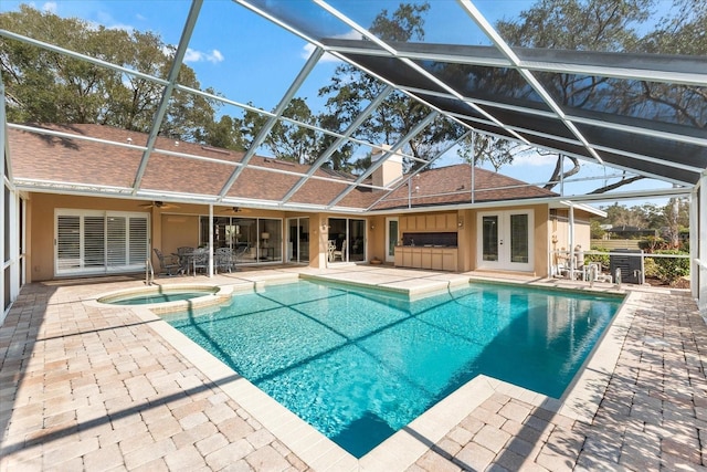 view of swimming pool with a ceiling fan, a lanai, french doors, a patio area, and a pool with connected hot tub