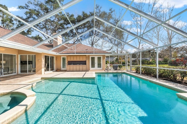 view of pool featuring french doors, a patio area, a pool with connected hot tub, and a lanai