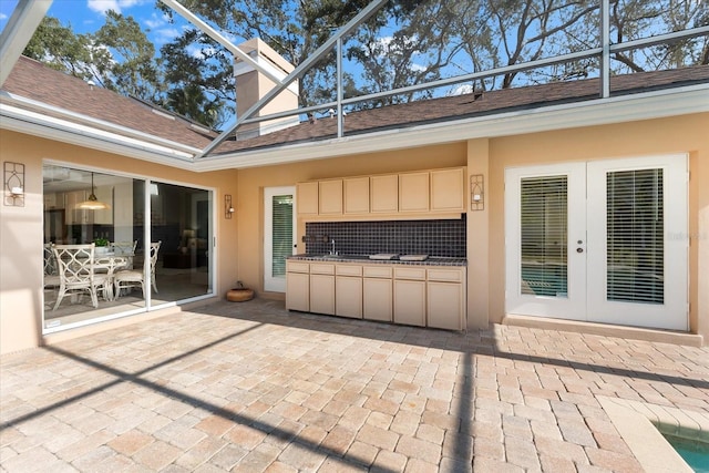 view of patio / terrace with a sink, french doors, and a lanai