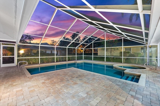 pool at dusk with a lanai, a patio area, and a pool with connected hot tub