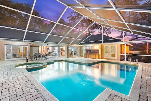 view of swimming pool with glass enclosure, a pool with connected hot tub, a patio, and french doors