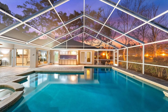 view of swimming pool with glass enclosure, french doors, a patio area, and a pool with connected hot tub