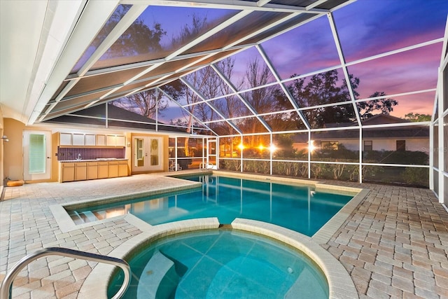 view of pool with a lanai, a patio area, a pool with connected hot tub, and french doors