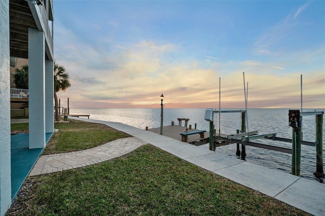 view of dock with a water view and a lawn