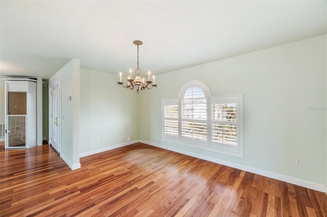 unfurnished room featuring a notable chandelier and wood-type flooring