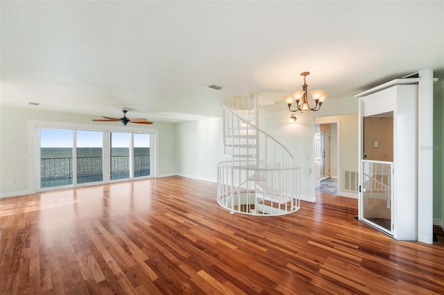 unfurnished room with ceiling fan with notable chandelier, wood-type flooring, and a water view