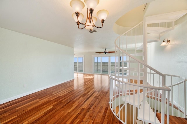 staircase featuring hardwood / wood-style flooring and ceiling fan with notable chandelier