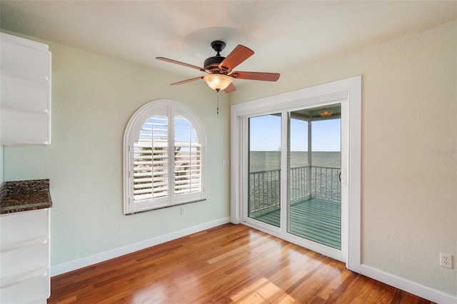 unfurnished dining area with a water view, ceiling fan, and hardwood / wood-style flooring