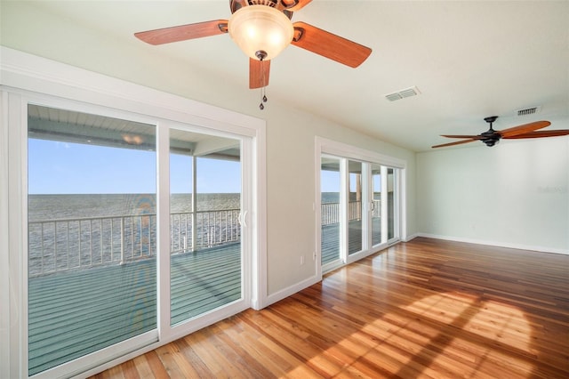 spare room featuring a water view, hardwood / wood-style flooring, and a wealth of natural light