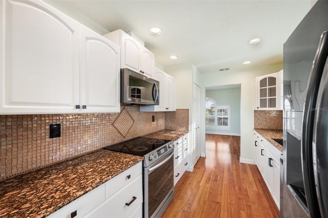 kitchen featuring white cabinetry, appliances with stainless steel finishes, and dark stone countertops