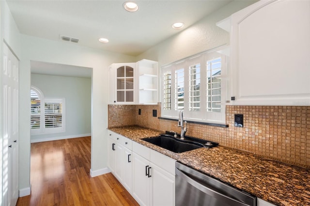 kitchen featuring sink, dishwasher, white cabinetry, dark stone counters, and light wood-type flooring