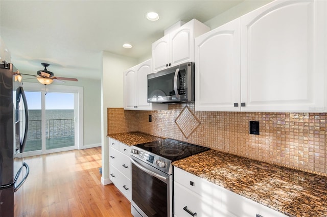 kitchen with white cabinetry, dark stone countertops, decorative backsplash, stainless steel appliances, and light hardwood / wood-style flooring