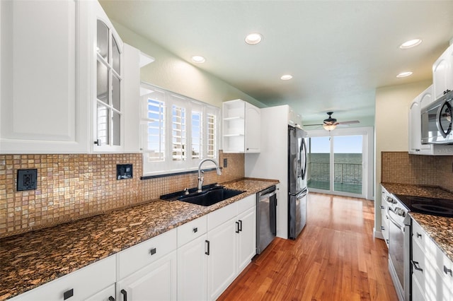 kitchen featuring sink, appliances with stainless steel finishes, dark stone countertops, backsplash, and white cabinets