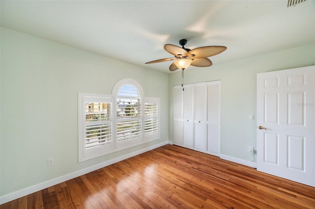 unfurnished bedroom with ceiling fan, wood-type flooring, and a closet