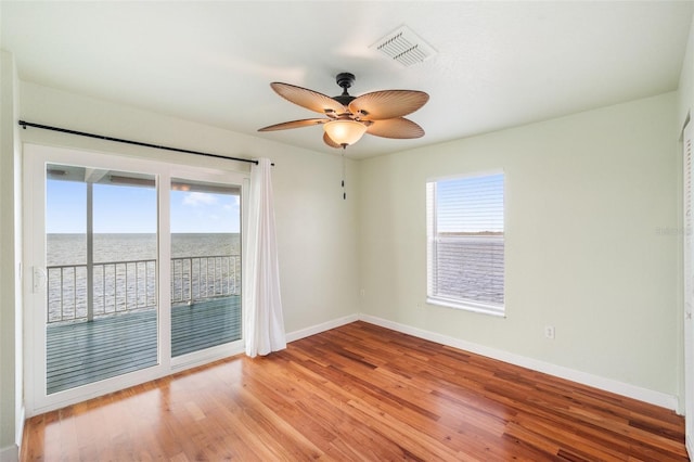 empty room with a water view, ceiling fan, and light hardwood / wood-style flooring