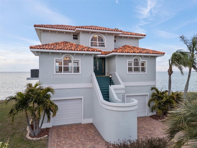 mediterranean / spanish-style house with a garage and a water view