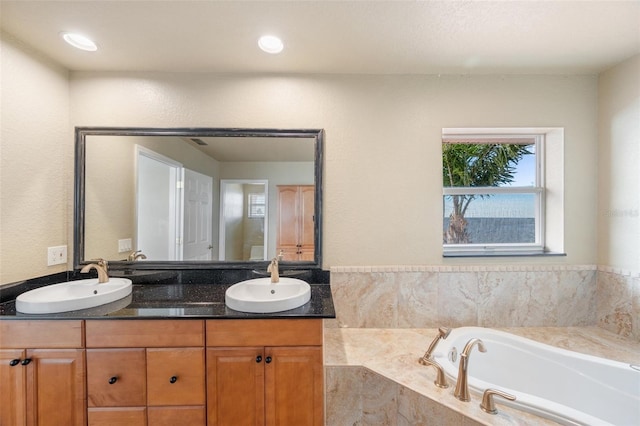 bathroom with vanity and tiled tub