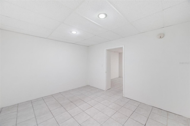 spare room featuring a drop ceiling and light tile patterned floors